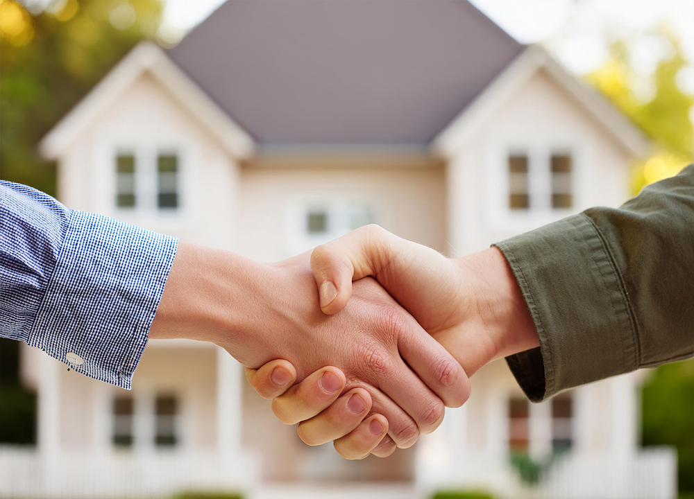 Close up of handshake with house for sale in background